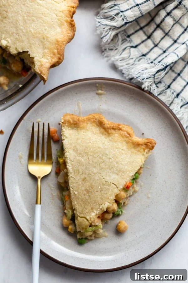 Hearty Vegan Chickpea Pot Pie 4 Overhead shot of a baked vegan pot pie on a white plate, with a crimped crust and a simple X venting pattern.