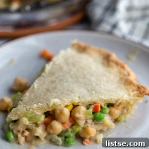 slice of chickpea pot pie filled with chickpeas and veggies with the full pie in the background