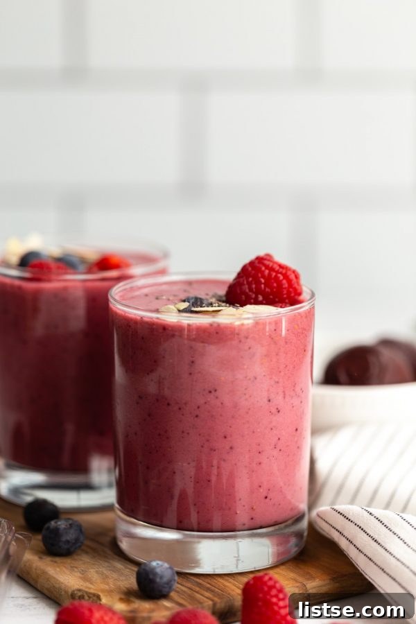 Side shot of a gorgeous beet smoothie, artfully topped with fresh mixed berries and delicate almond slices, showcasing its inviting texture.