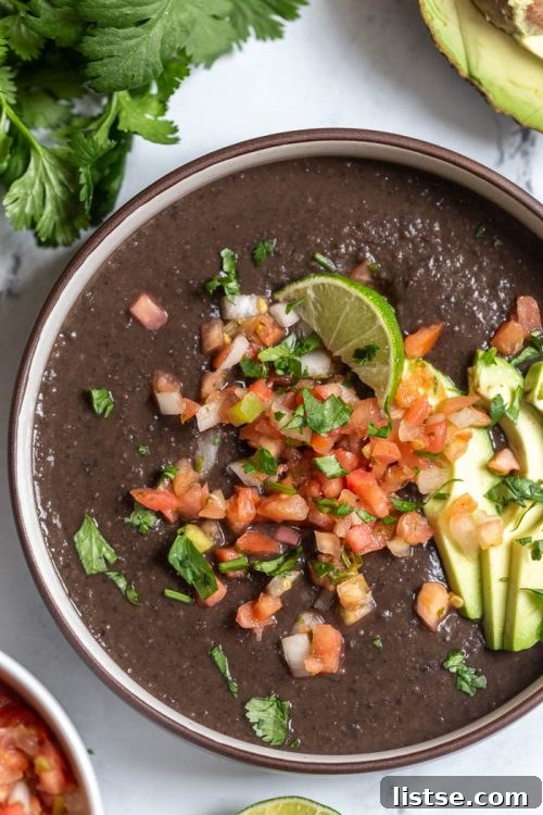 Creamy black bean soup topped with pico de gallo, avocado, and lime
