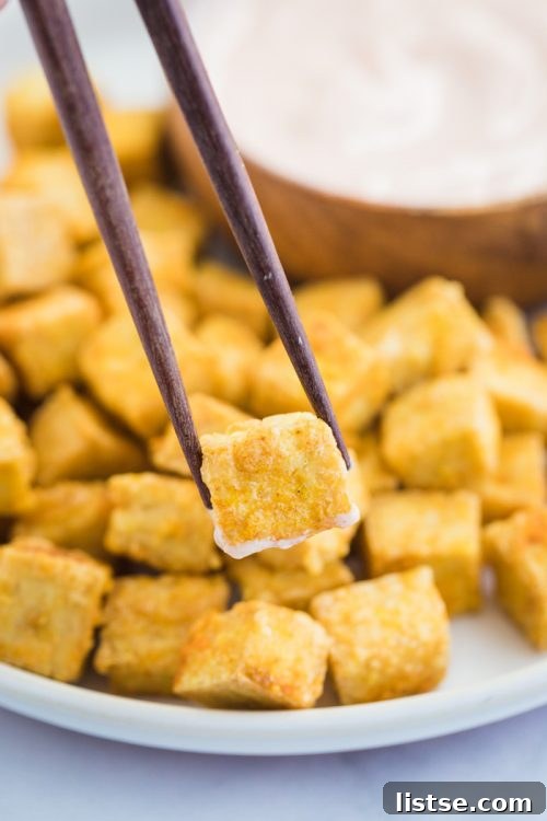 Perfectly crispy baked tofu cube held by chopsticks