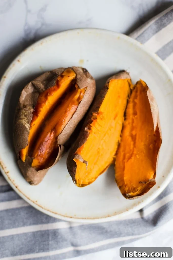 top down shot of 2 cooked sweet potatoes split open and sitting on a plate