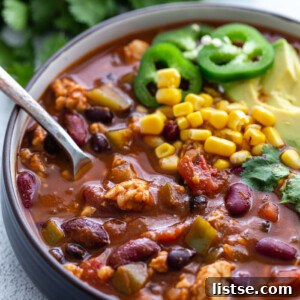 Tempeh chili topped with sliced jalapeños and fresh cilantro, served in a rustic bowl.