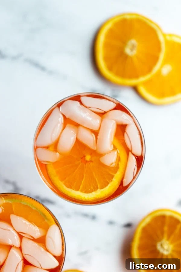 Timeless Aperol Spritz 3 A close-up of an Aperol Spritz cocktail in a stemmed wine glass, featuring its characteristic orange hue and an orange slice garnish, on a polished marble surface.