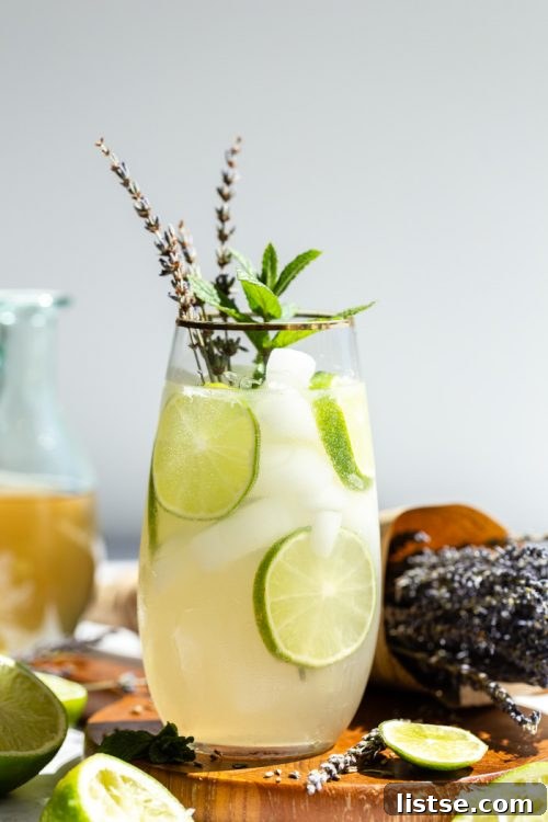 An exquisitely crafted Lavender Mojito cocktail in a tall glass, garnished with vibrant mint leaves, lime, and a delicate sprig of lavender for aromatic appeal.