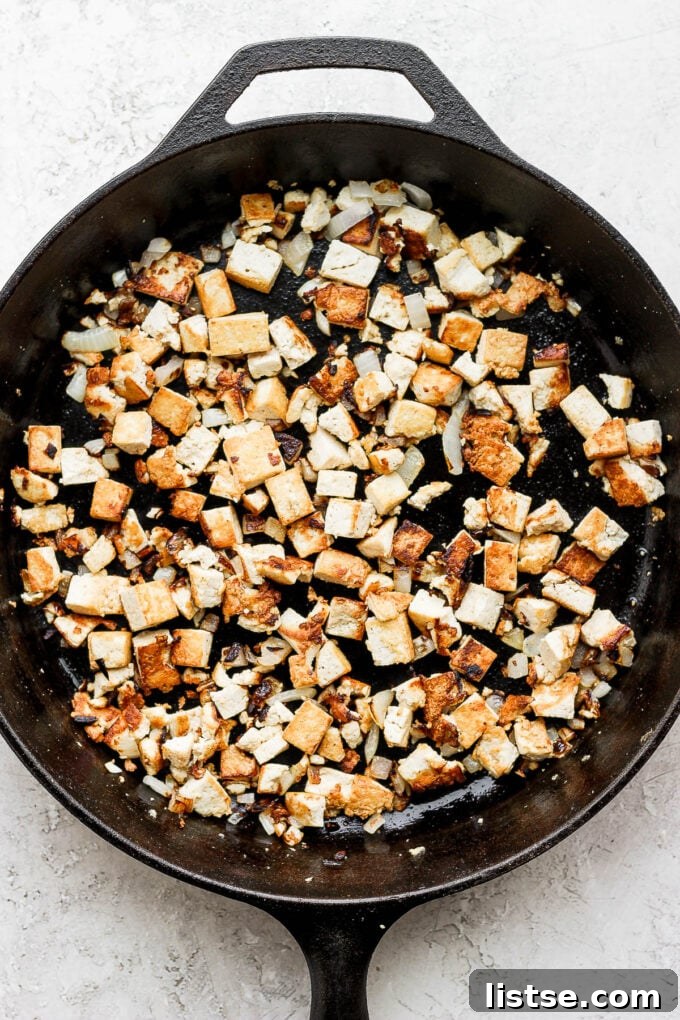Sautéing crumbled tofu and onions in a skillet