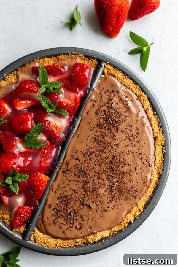 Sweet Divide Pie: Strawberry & Chocolate 6 Double-sided 'split decision pie' showcasing a chocolate silken pie on one side and a fresh strawberry pie on the other. Fresh strawberries and mint leaves are artfully arranged around the edges of the pie, enhancing its visual appeal.
