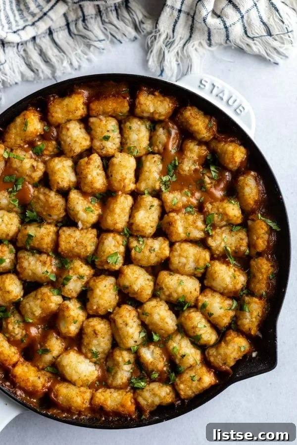 Delicious Vegan Tater Tot Casserole fresh out of the oven, topped with crispy golden tater tots and garnished with fresh herbs.