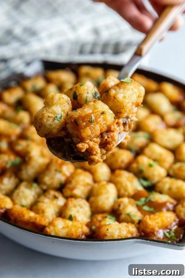 The assembled Vegan Tater Tot Casserole, topped with a generous layer of frozen tater tots, perfectly arranged and ready for baking in the oven.