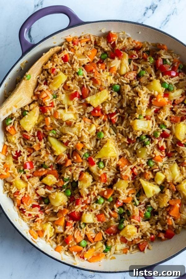 Golden Pineapple Fried Rice 2 top down shot of fried rice in a large skillet with peas, pineapple, red bell pepper, and carrot, showcasing vibrant colors and fresh ingredients