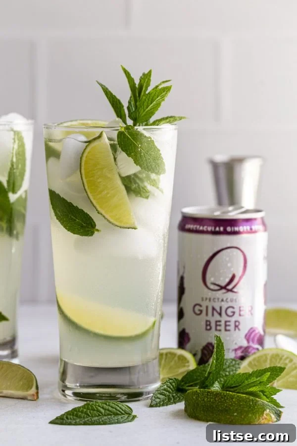 Refreshing Ginger Beer Mojito with Q Ginger Beer can, lime wedges, and mint sprigs