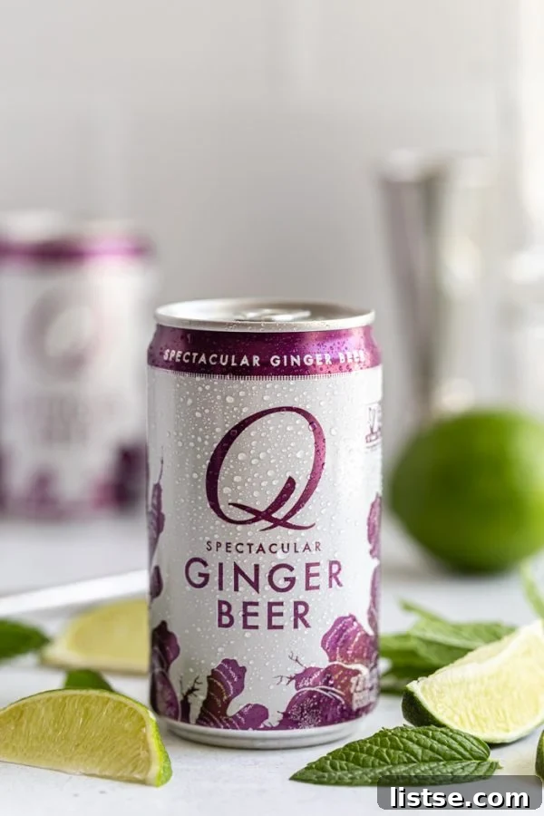 Close-up of a Q Mixers Ginger Beer can, surrounded by fresh lime wedges and mint sprigs, highlighting the premium mixer