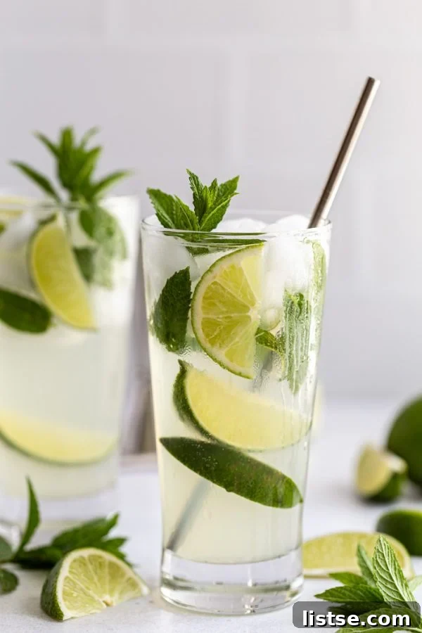 Close-up of a freshly made Ginger Beer Mojito, garnished with mint and lime, with lime wedges and mint sprigs scattered around