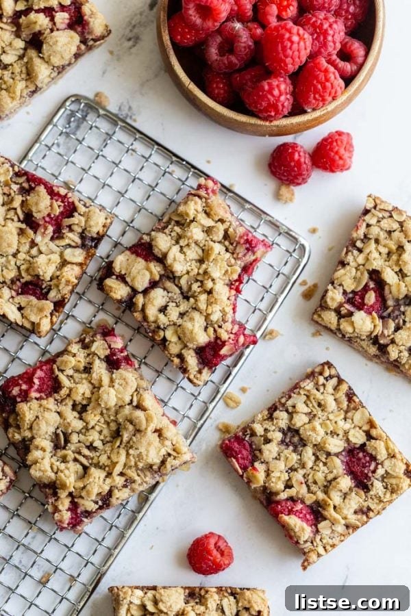 Four delicious vegan raspberry crumble bars arranged on a serving plate.