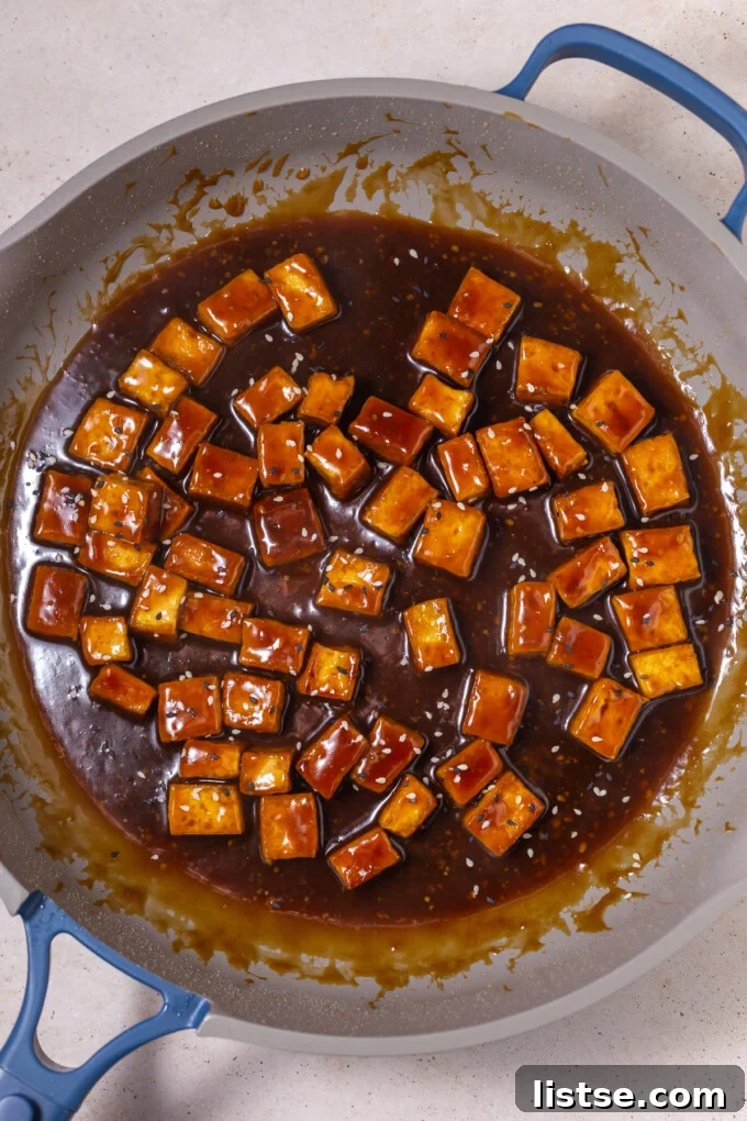 crispy tofu in a large skillet with sesame sauce on it and sesame seeds