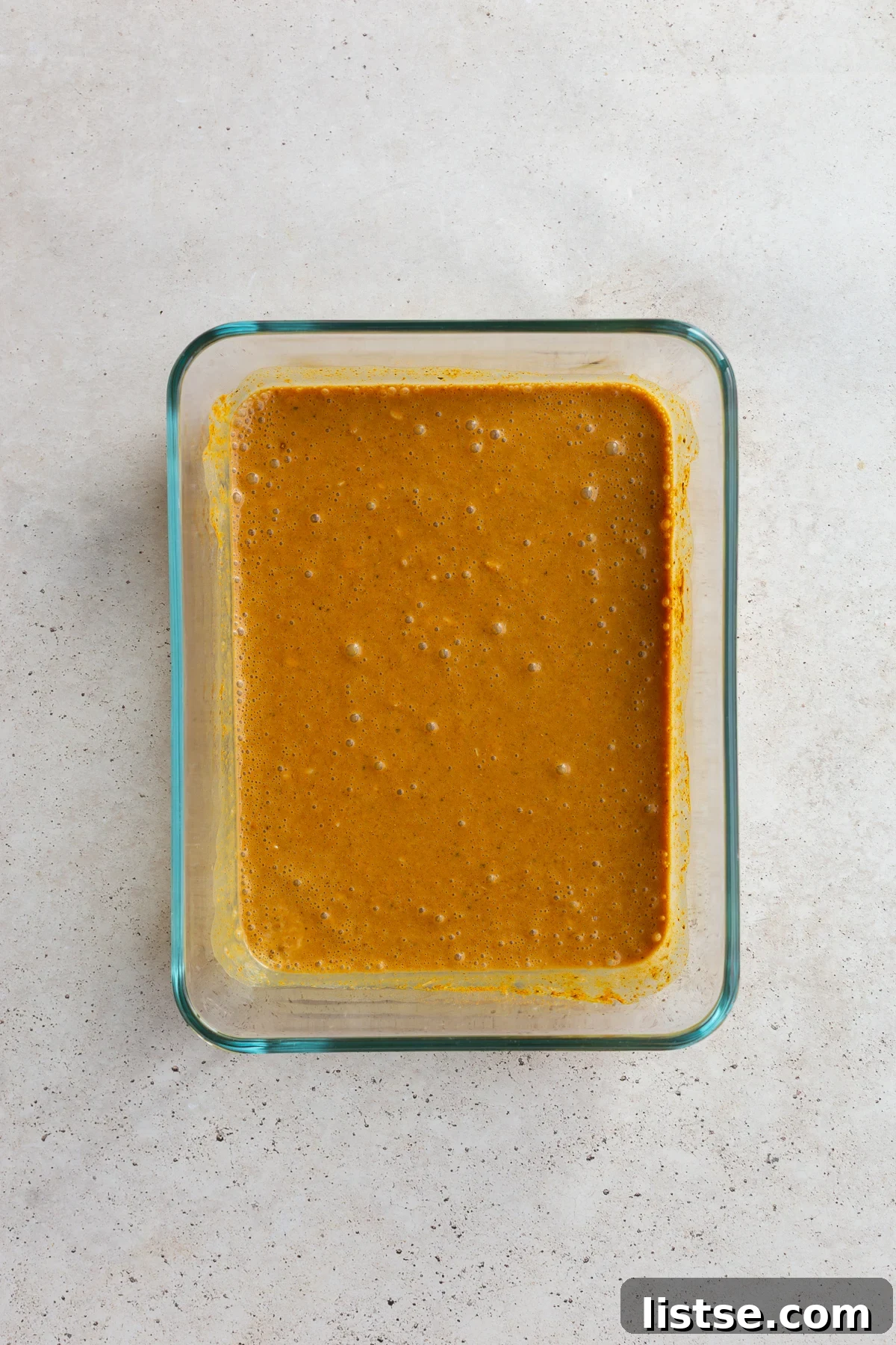 Golden Tofu Satay with Velvety Peanut Sauce 6 A glass dish filled with a creamy, spiced marinade, ready for tofu.