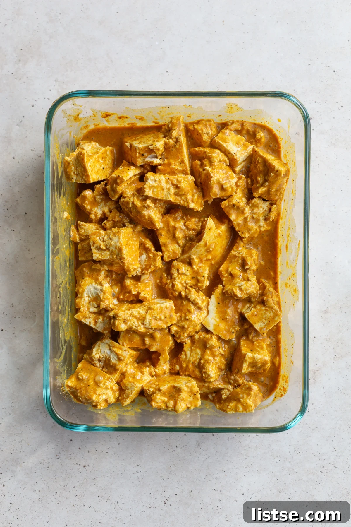 Golden Tofu Satay with Velvety Peanut Sauce 7 Thawed tofu cubes marinating in a glass dish, absorbing rich flavors.