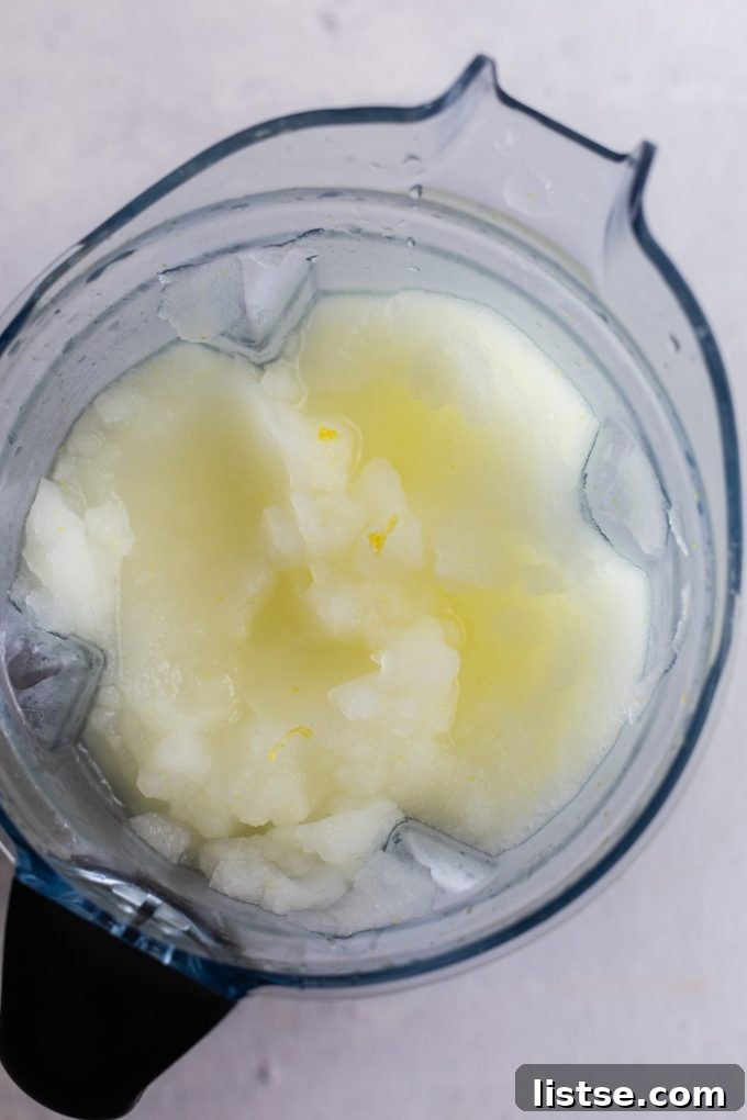 Two glasses of Boozy Frozen Lemonade on a wooden surface, ready to be enjoyed.