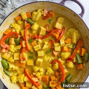 Tofu coconut curry simmering in a large skillet, with a kitchen napkin visible in the corner.