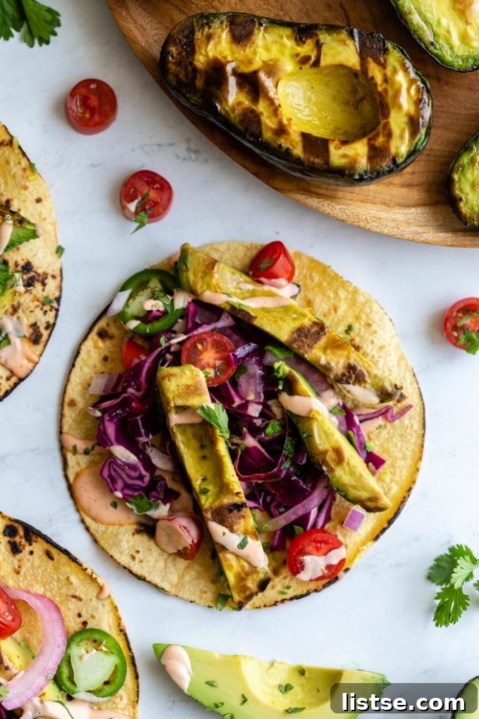 Overhead shot of grilled avocado tacos arranged on a rustic wooden board, ready to be enjoyed.
