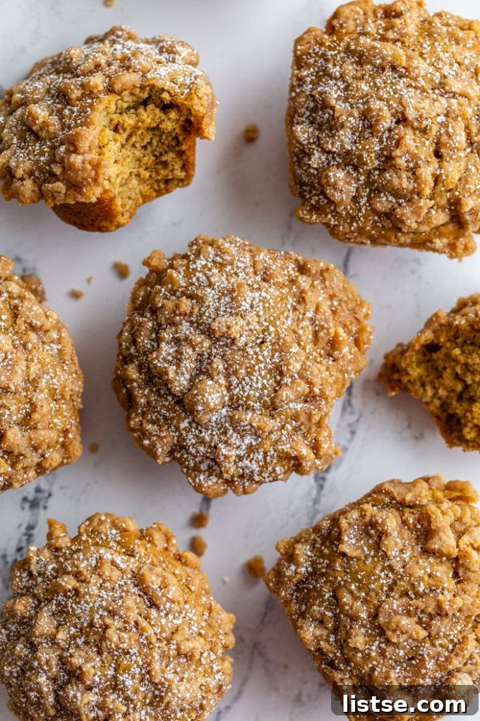 An overhead shot revealing a delightful array of Coffee Cake Banana Muffins, each crowned with a generous crumble and a delicate dusting of powdered sugar. They rest invitingly on a elegant marble board.