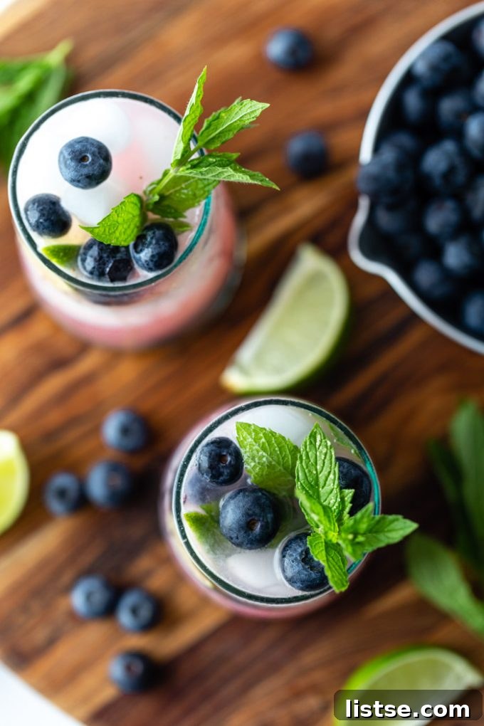 Overhead shot of two Blueberry Mojitos, beautifully arranged on a wooden serving board, highlighting the colorful ingredients and presentation.