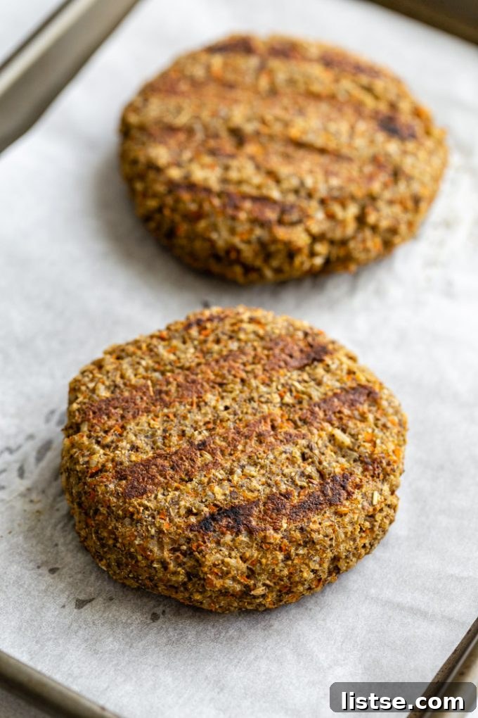 Irresistible Homemade Veggie Burgers 3 Up-close shot of two perfectly cooked veggie burger patties resting on parchment paper, displaying enticing char marks from the grill, promising a smoky flavor.