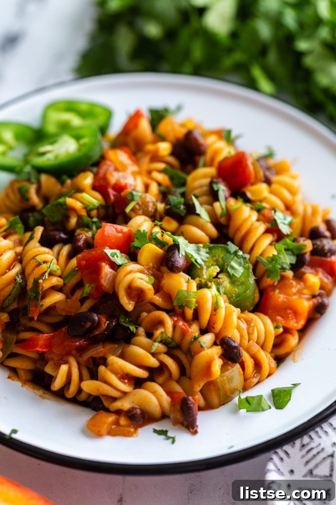 A large pot filled with creamy vegan taco pasta, with a spoon ready to serve.