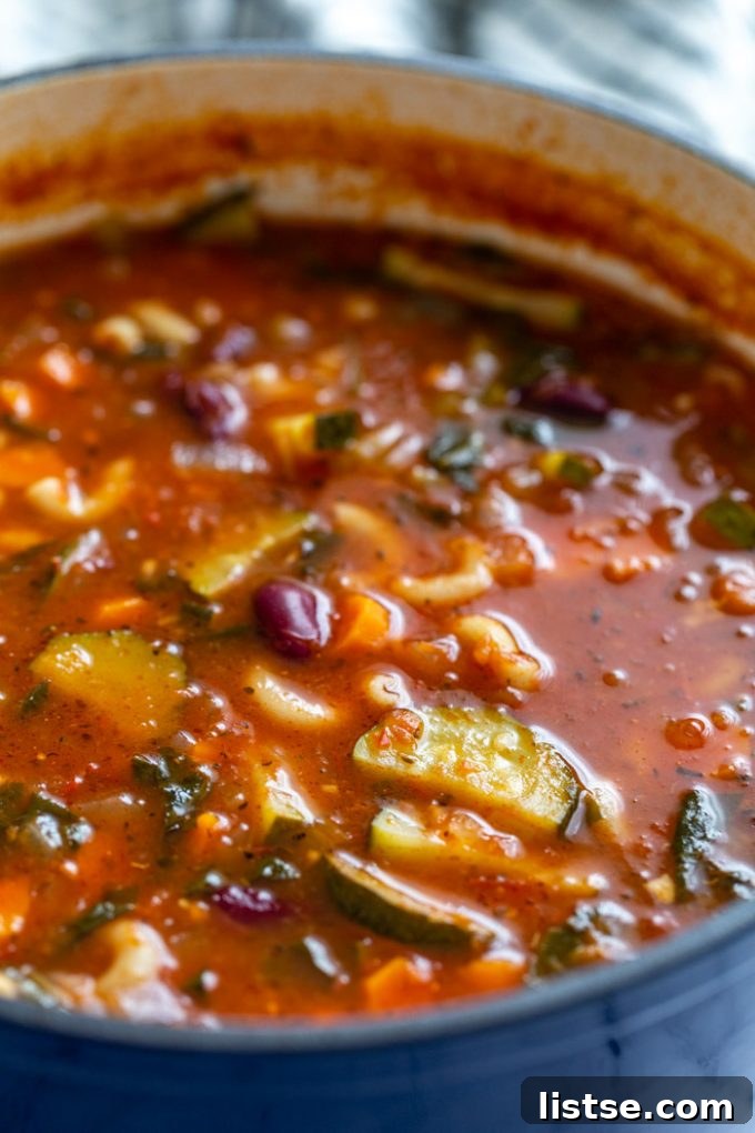 Hearty Vegan Minestrone 5 A close-up side view of piping hot vegan minestrone soup simmering in a large pot, showcasing its vibrant colors and hearty texture.