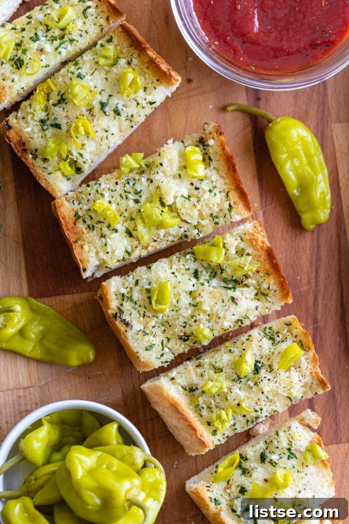 Spicy Peperoncini Garlic Bread 2 Sliced garlic bread topped with chopped peperoncini peppers, with a bowl of marinara sauce in the corner.