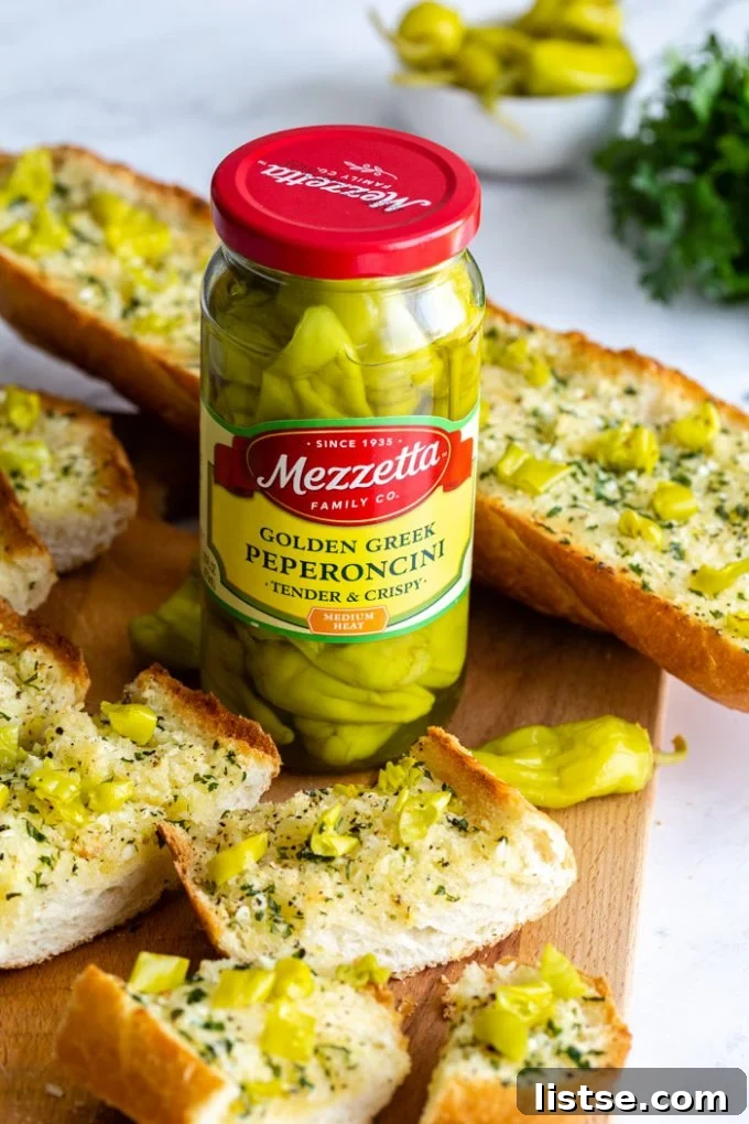 Spicy Peperoncini Garlic Bread 3 Sliced garlic bread with peperoncini peppers, with a jar of Mezzetta Golden Greek Peperoncini in the foreground.