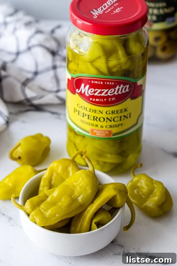 Spicy Peperoncini Garlic Bread 5 A close-up of a jar of Mezzetta Golden Greek Peperoncini peppers, with a bowl of the peppers in front.