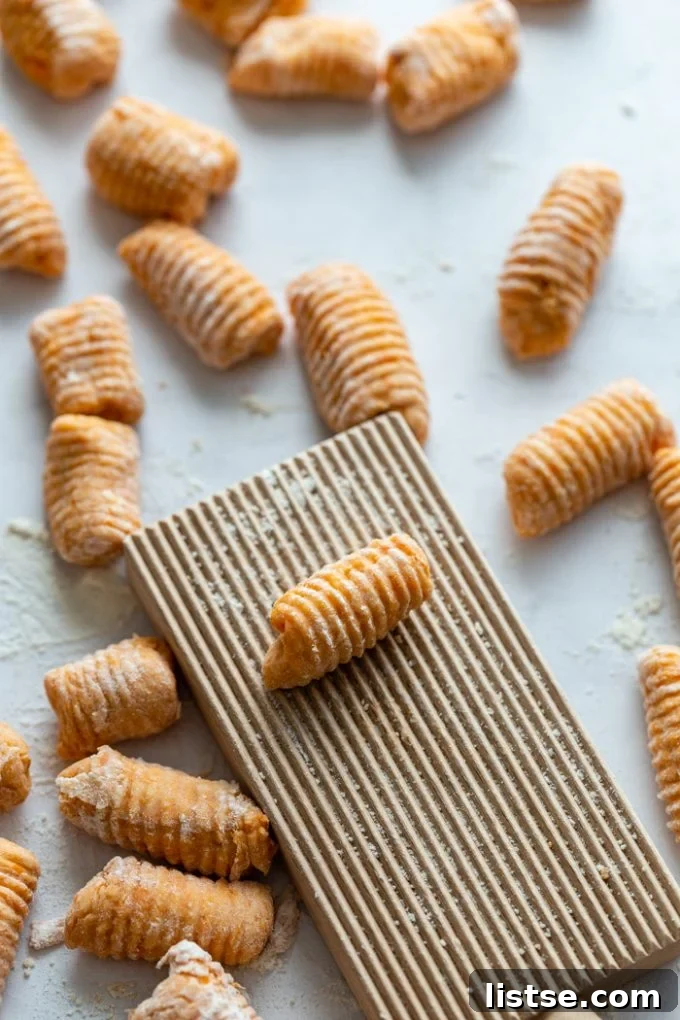 up close side shot of raw sweet potato gnocchi on a gnocchi board
