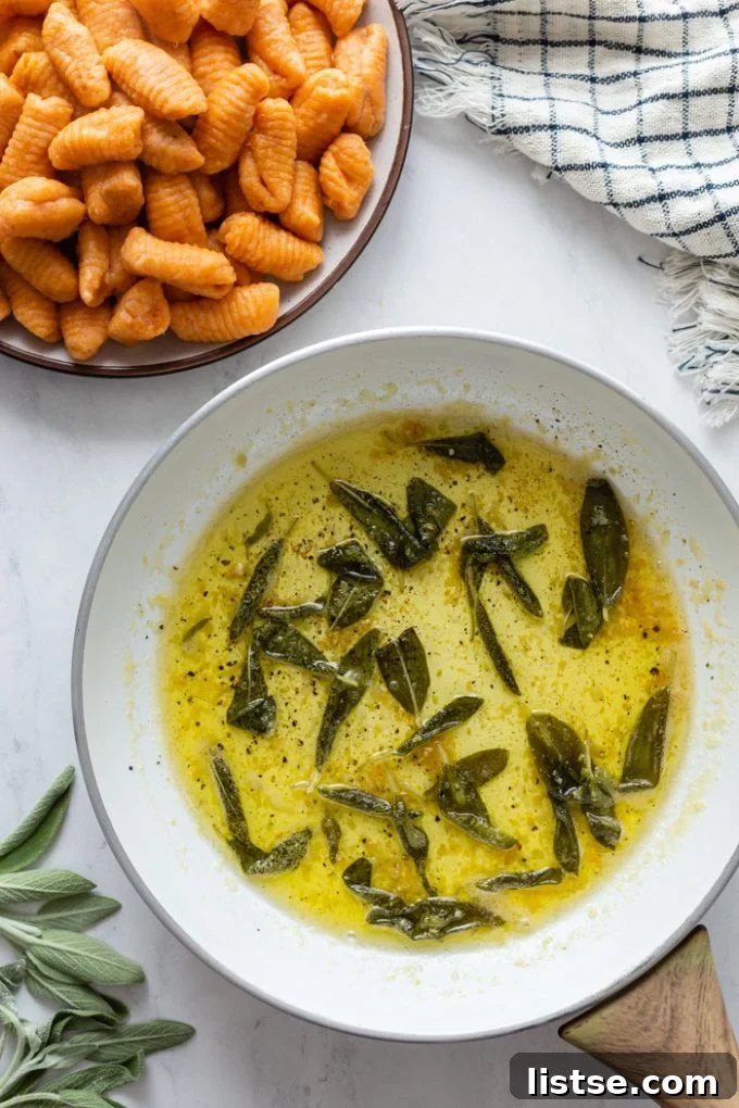 sage butter sauce in a white skillet with sweet potato gnocchi in a bowl next to it