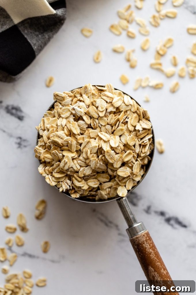 top down shot of rolled oats in a measuring cup with a wooden handle