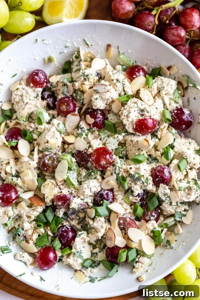 white bowl filled with "vegan chicken salad" that has chunks of tofu, veggies and grapes in it