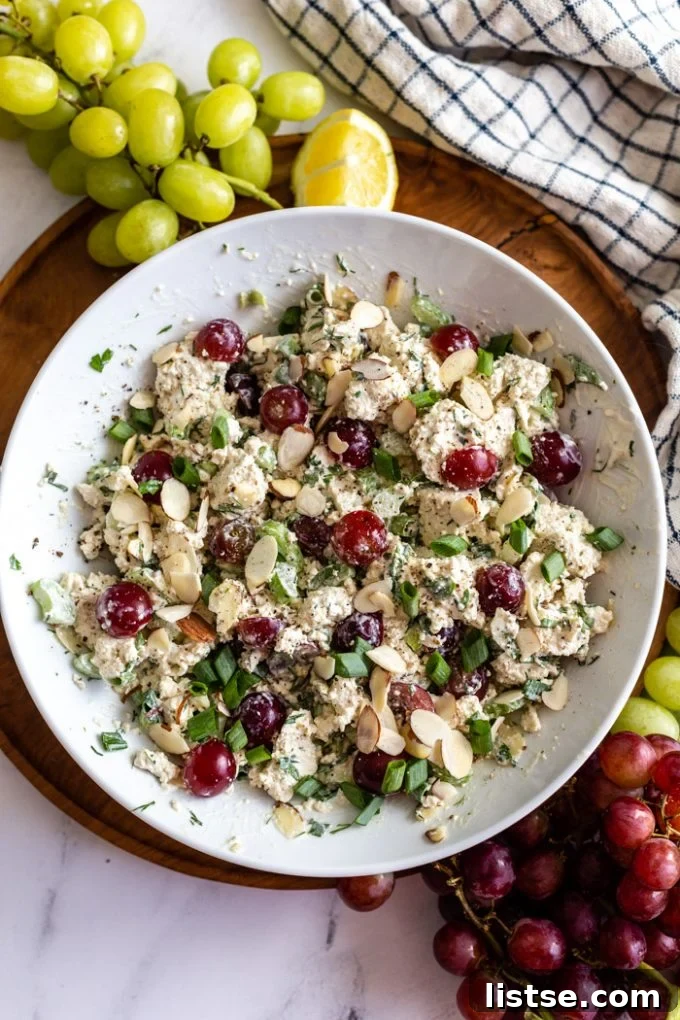 white bowl filled with "vegan chicken salad" that has chunks of tofu, veggies and grapes in it