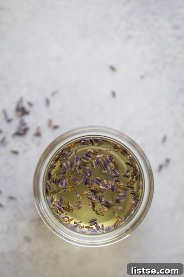 Sweet Serenity: Crafting Lavender Syrup 3 A small glass jar filled with clear lavender simple syrup, adorned with fresh lavender sprigs.