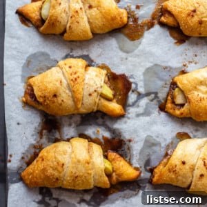 A single baked apple pie crescent roll, cut open to reveal the soft apple filling.