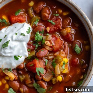 up close shot of instant pot vegetarian chill topped with fresh herbs and sour cream with chips in the background