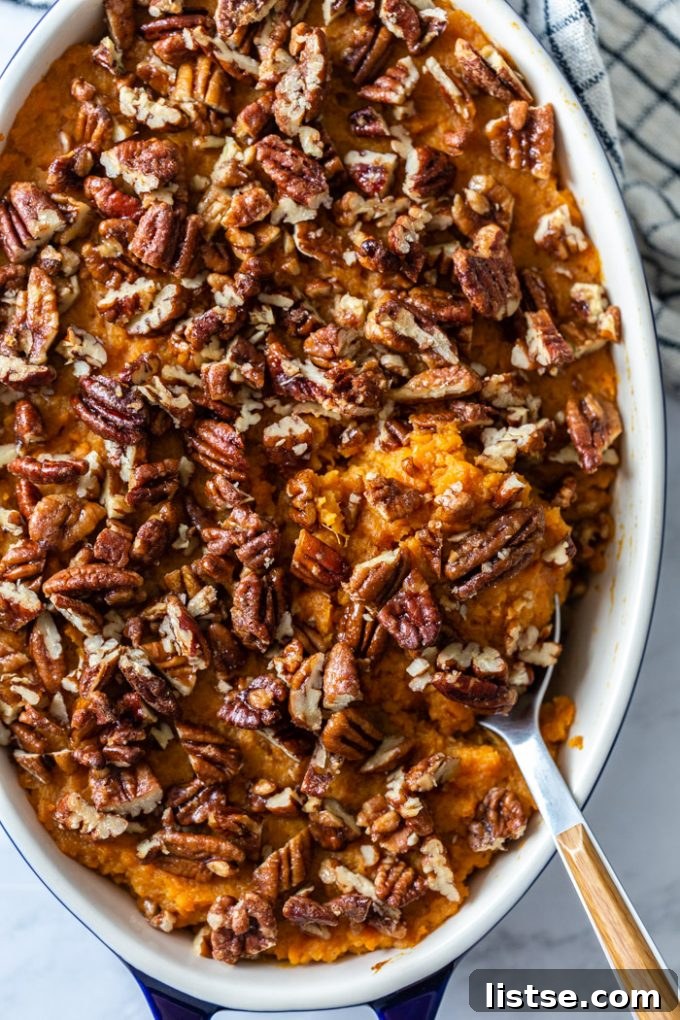 Wholesome Vegan Sweet Potato Bake 2 top down shot of vegan sweet potato casserole in a casserole pan topped with candied pecans, with a serving spoon on the side