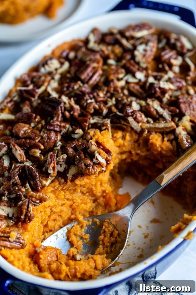 Wholesome Vegan Sweet Potato Bake 5 side view of a vegan sweet potato casserole in a baking dish, with a scoop removed and a spoon in the dish