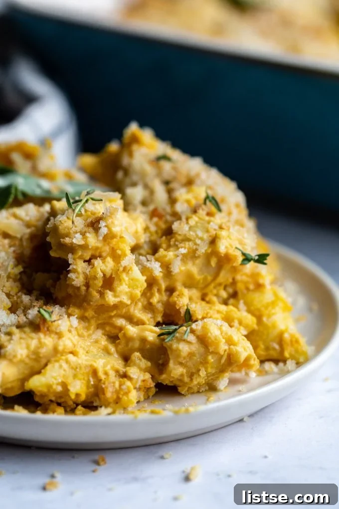 Close-up shot of a serving of baked vegan mac and cheese on a plate, garnished with fresh thyme