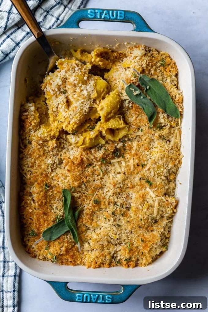 Teal colored casserole dish filled with bubbling baked vegan mac and cheese, topped with fresh herbs
