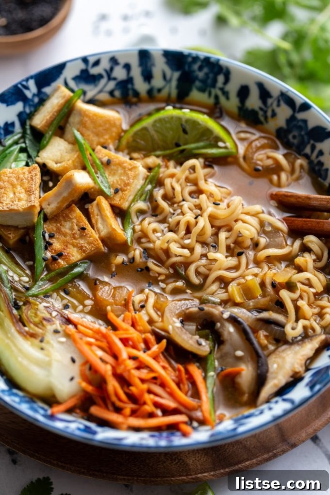 Bowl filled with savory vegan ramen noodles, sliced mushrooms, shredded carrots, and vibrant bok choy.
