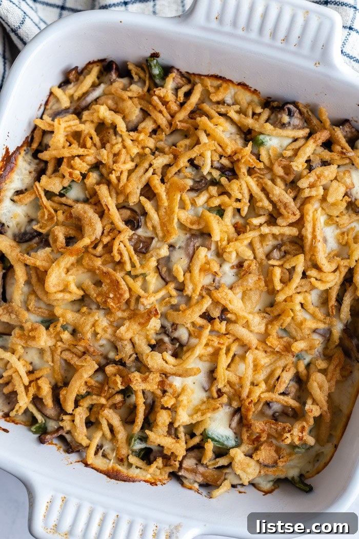 A serving spoon gracefully lifts a generous portion of creamy vegan green bean casserole, showcasing its rich texture and topping.