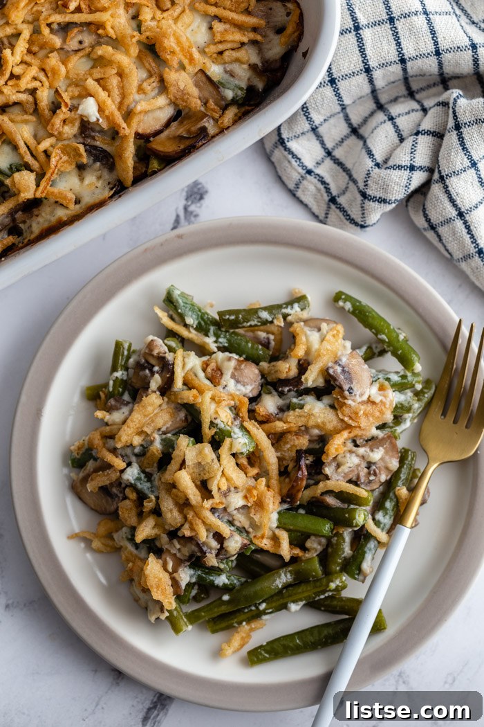 A generous serving of vegan green bean casserole on a plate, topped with golden-crisp fried onions, ready to be enjoyed.