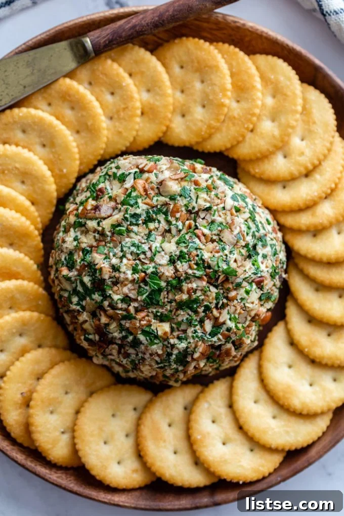 A beautifully presented vegan cheeseball, encircled by an elegant ring of various crackers on a serving plate.