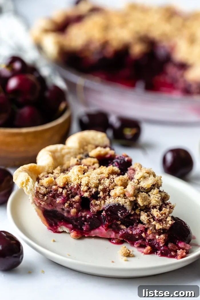 slice of cherry crumble pie on a plate with more slices in the background