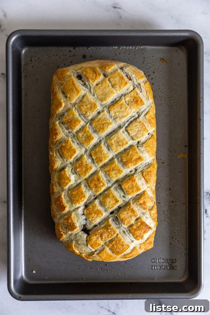 A golden-brown vegan Wellington, fresh out of the oven, resting on a Chicago Metallic baking sheet, highlighting its perfect crust and inviting texture.